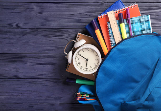 istock Stationery and alarm clock in a school backpack. Learning concept, time to school 1257228411
