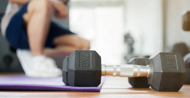 istock close up on dumbbell with young man sitting over exercise mat on the floor while to resting after workout at home for new normal healthy lifestyle concept 1257231765