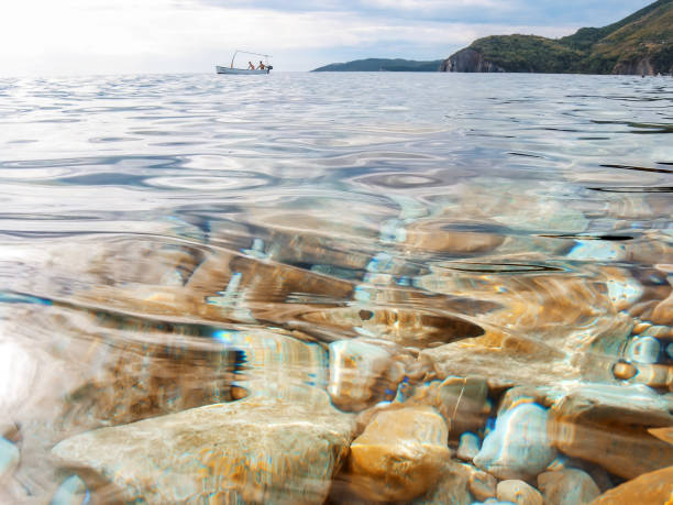 Sea stones in the sea water. Pebbles under water. The view from the top. Nautical background. Clean sea water. Transparent sea.