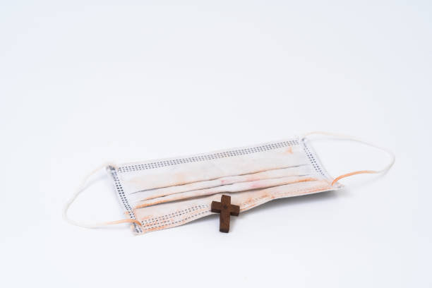 istock Used face mask and wood cross 1257234668