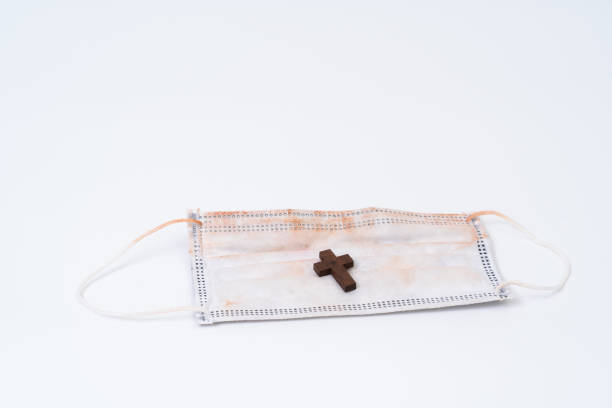 istock Used face mask and wood cross 1257234727