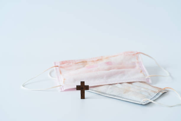 istock Used face mask and wood cross 1257234830
