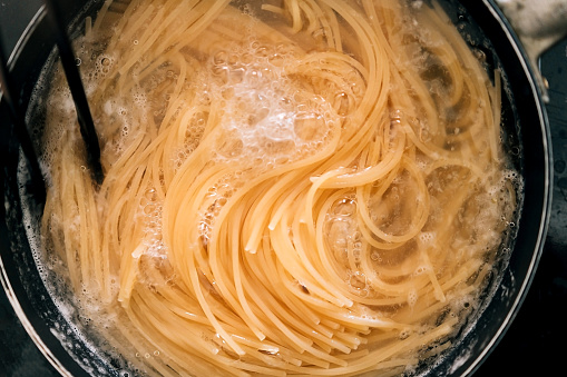 Close-up of spaghetti pasta In boiling hot water in steel pan. Preparation for making Al Dente Spaghetti.