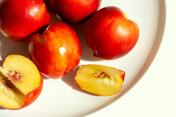 frutas de nectarina orgânica maduras vermelhas na placa branca no fundo da natureza. conceito de alimentação saudável no verão. antioxidante de frutas. foco seletivo. vista superior - zeaxanthin - fotografias e filmes do acervo