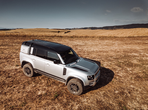 Torrita di Siena, Italy - July 12, 2020 : The New Land Rover Defender 2020 is parked on a wheat field