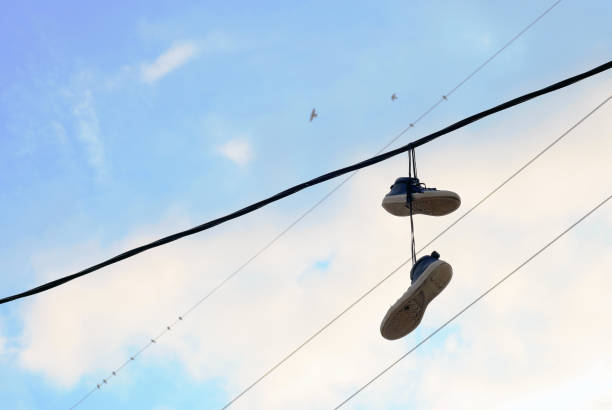 Sports shoes dangling on electric wires stock photo