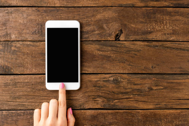 istock Woman’s hand using smart phone with empty screen on rustic wooden background. Close up 1257244183