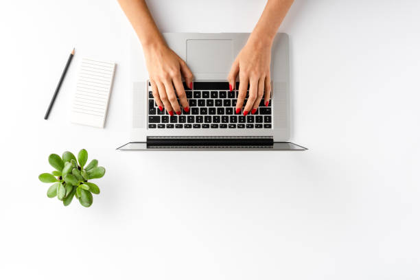 istock Overhead shot of woman’s hands working on laptop on white table with accessories. Office desktop. Flat lay 1257244501