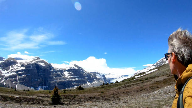 istock Man hikes up mountain ridge and looks off to distant scene 1257245461