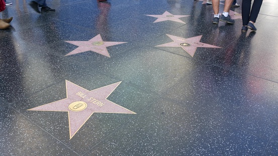 LOS ANGELES, CALIFORNIA, USA - 7 NOV 2019: Walk of fame promenade on Hollywood boulevard in LA. Pedastrians walking near celebrity stars on asphalt. Walkway floor near Dolby and TCL Chinese Theatre.