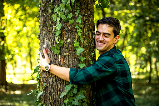 Smiling Man embracing tree woods autumn
