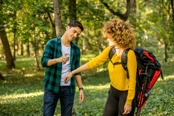 homme utilisant le jet anti-moustique à l’extérieur au voyage de randonnée. plan rapproché de jeune touriste de routard féminin appliquant le jet d’insecte sur des mains - insect repellant mosquito bug bite spraying photos et images de collection