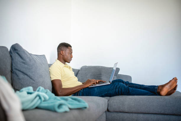 istock Young African Man using laptop in the living room 1257248287