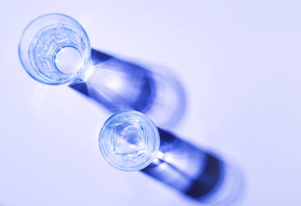 istock Glass glass with clean water on a light background with hard light and reflection. Distorted glass water 1257248702