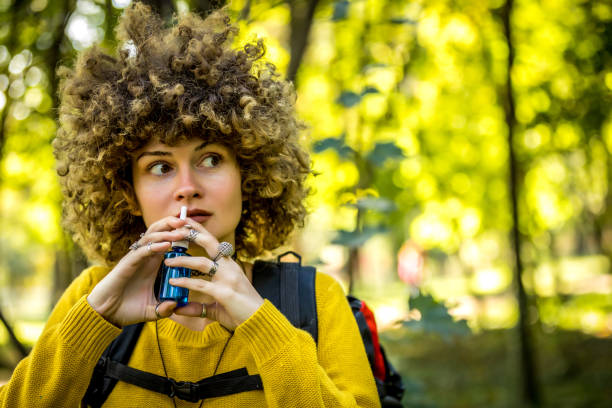 молодая женщина, используя нос спрей для аллергии на открытом воздухе - nasal spray allergy bottle body care стоковые фото и изображения