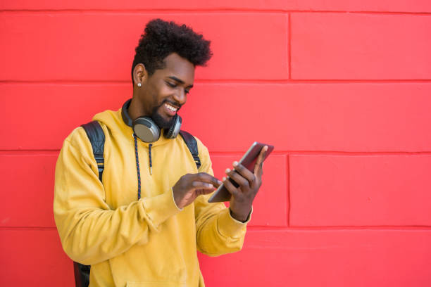 istock Afro man using his digital tablet with earphones. 1257249225