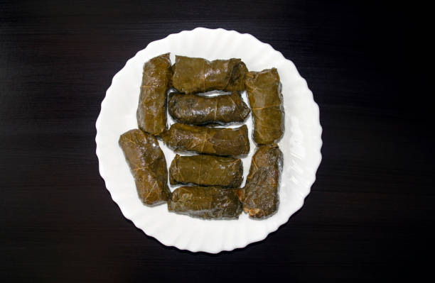 Stuffed Grape leaves on white plate on dark wooden background. Famous traditional Middle East, Turkish, Asian cuisine. Dolma