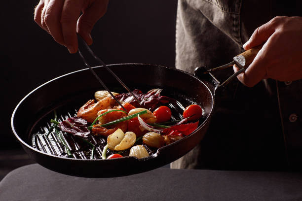 istock Chef cooks seafood, shrimp in a pan with vegetables. 1257253261