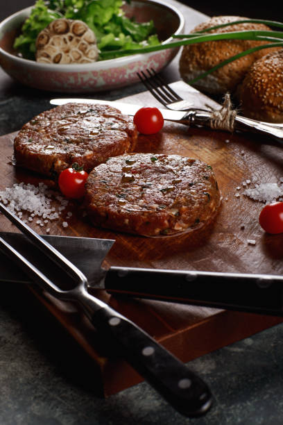 istock Raw Ground beef meat Burger steak cutlets with ingredients on the board. 1257253460