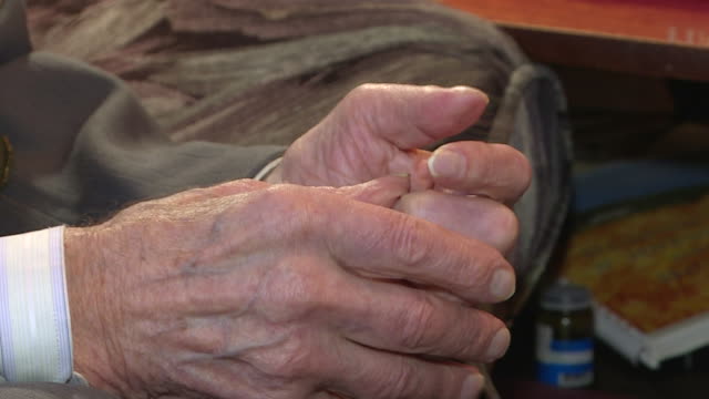 Close-up of the old man's hands with the wrinkled skin shaking .