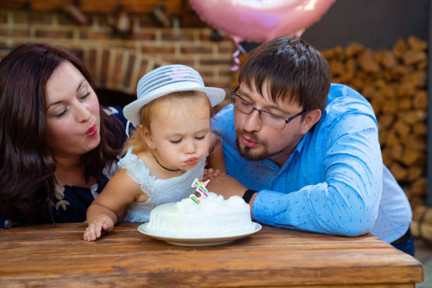 istock parents with daughter blowing out candle on cake. 1257254409