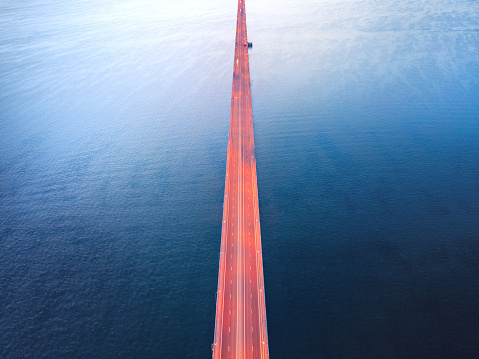 Endless illuminated bridge over dark water. Aerial view