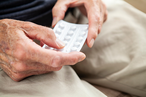 Close-up of an old person's hands holding a blister pack of pills