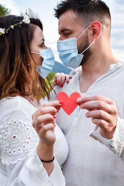 istock Just married couple holding a heart, wearing face 1257260460
