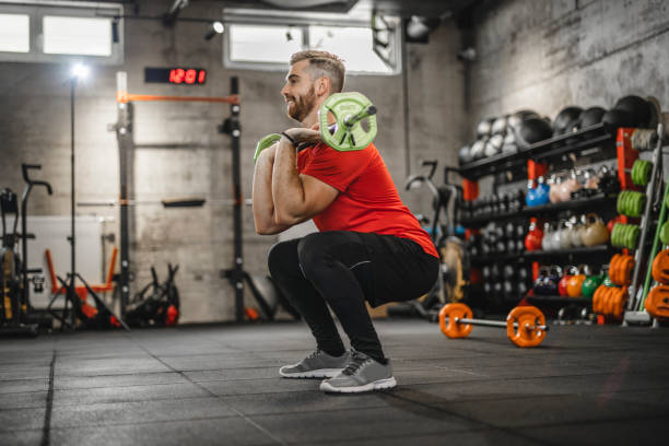 Young man on a cross training in the gym. He is doing snatch weightlifting. Young man on a cross training in the gym. He is doing snatch weightlifting. barbel stock pictures, royalty-free photos & images