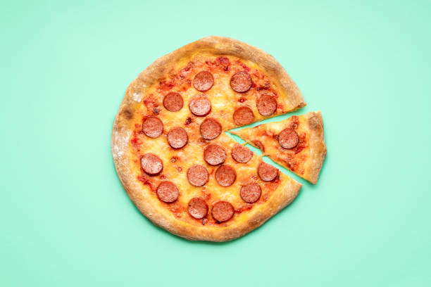 istock Pepperoni pizza top view on a green background. Sliced pizza above view 1257262702