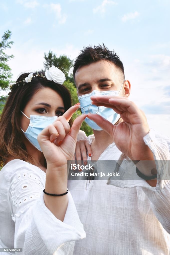 Just married couple holding their wedding rings wearing face masks Married couple outdoors with face masks Adult Stock Photo