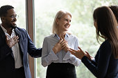 Middle-aged businesswoman get congrats and compliments from multiethnic colleagues