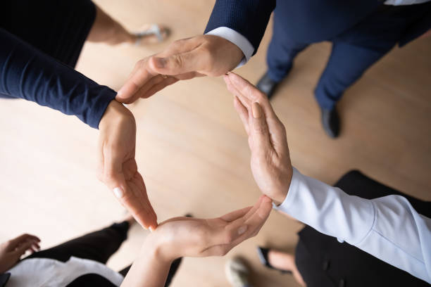 istock Four businesspeople standing together puts palms together making circle shape 1257268426