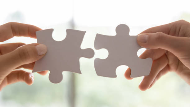 istock Closeup view women hands holding pieces join puzzles having fun 1257268429