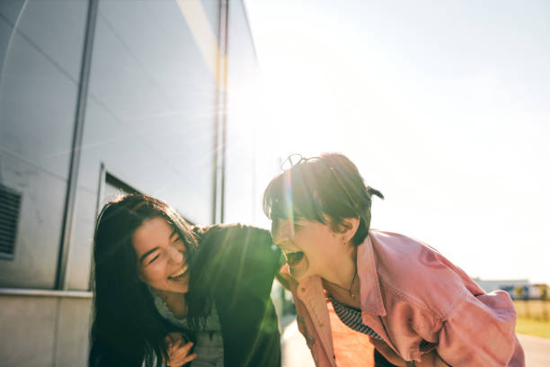 Cheerful sisters telling stories and laughing outdoors on a sunny day