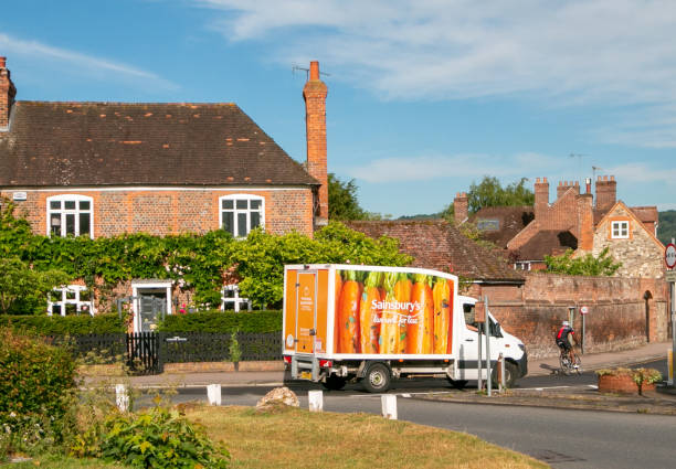 Sainsbury's Delivery Van in Otford, England, with a cyclist in the road. Sainsbury's is a large supermarket retail brand in the UK.