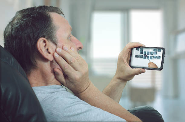 Mature man suffers toothache. He contacted the dental clinic with telemedicine application. stock photo