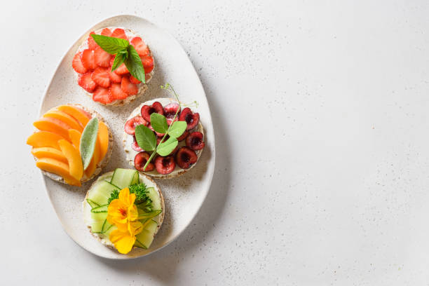istock Puffed rice cakes with different toppings friuts and vegetables on white. Vegan snacks. Vertical format. 1257272273