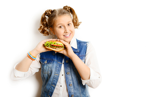 schoolgirl eating burger on white background