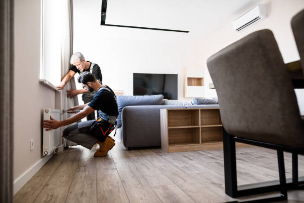 istock Full length shot of two professional plumbers, workers in uniform fixing or installing heating radiator. Construction, maintenance and repair concept. 1257274744