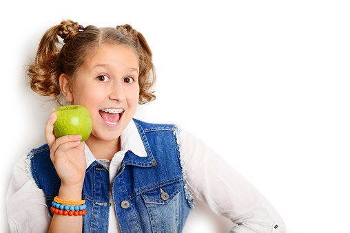 schoolgirl eating an apple on white background