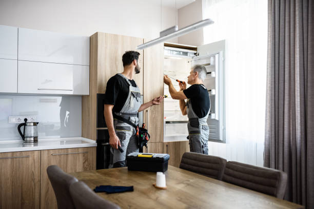 istock Adding care to your technologies. Aged repairman in uniform fixing refrigerator in the kitchen, while his colleague helping him, bringing screwdriver. Repair service concept 1257274950
