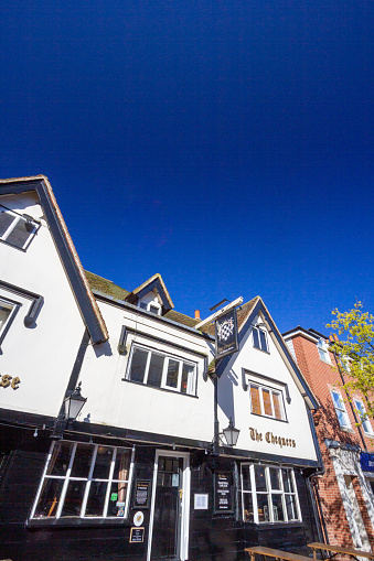 The 16th century house on Sevenoaks High Street is known as The Chequers and is a popular pub. Other shops' names and logos are visible as well as the pub's coat of arms.