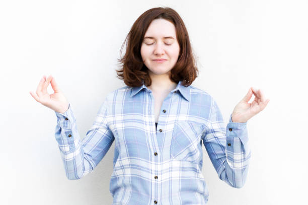 istock girl smiling, standing meditating with closed eyes on white background 1257275991