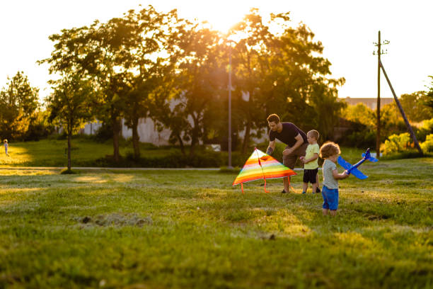 istock Father helping to older son how to lunch a kite while his younger son playing with airplane toy 1257276130