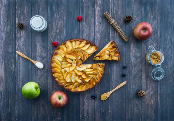 Homemade apple pie surrounded by ingredients on a old wooden surface. Top view Gastronomic concept Homemade apple pie surrounded by ingredients on a old wooden surface. Top view Gastronomic concept. apple pie a la mode stock pictures, royalty-free photos & images