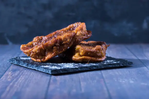 Photo of Homemade torrijas on a slate plate and wooden surface. Gastronomic concept.