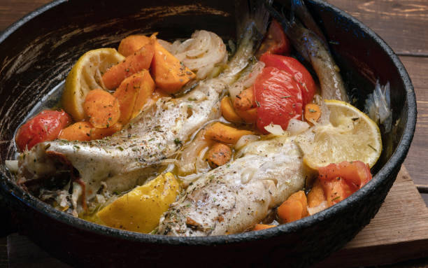 istock Stewed pollocks with vegetables and  lemons in panon brown table. 1257277502