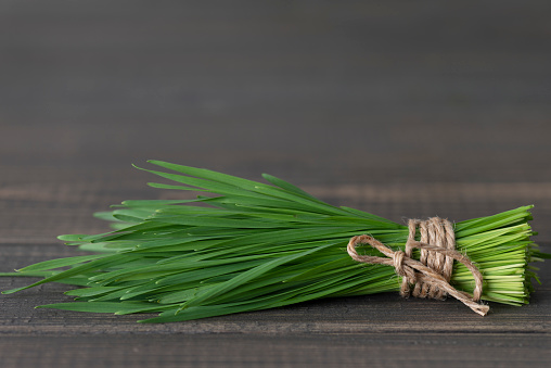 A bundle of wheatgrass on wooden background.