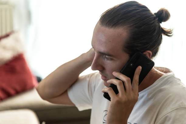 istock Handsome young man talking on the phone at living room 1257278020